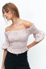 Crop top lila con escote off-shoulder, punto panal en el torso y mangas elastizadas con volados.