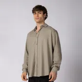 Camisa de manga larga color beige, confeccionada con mezcla de rayón y lino, con cuello abierto y cierre frontal de botones.