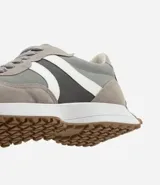 Championes estilo jogging con diseño de paneles en tonos gris, blanco y negro. Presentan cierre por cordones, suela de goma con relieve que se extiende hacia el talón y acabado en poliuretano.