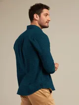 Camisa celeste a cuadros con cuello abotonado, manga larga y bolsillo en el pecho.