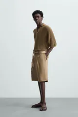 Polo manga corta color marrón, de punto con 17% de lino y cuello solapa con abertura frontal.