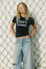 Remera negra de efecto lavado con corte slim fit, cuello redondo y manga corta. Cuenta con un estampado frontal con la frase "100% ICONIC" hecha con aplicaciones de brillos plateados.