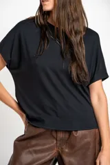 Remera negra de corte oversize, con mangas cortas y cuello redondo, confeccionada en tejido de viscosa y elastano de caída fluida.