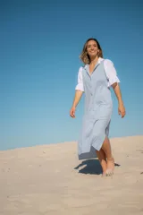 Vestido camisero largo celeste con cuello y mangas cortas abullonadas blancas.