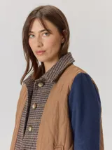 Campera de diseño híbrido con frente acolchado en color tostado, solapas y cuello en tejido de lana con patrón de cuadros tipo príncipe de gales, y mangas en paño de lana color azul marino. Cuenta con cierre frontal de botones.