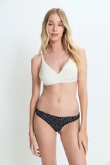 Bombacha tipo colaless de color negro con estampado de lunares blancos, confeccionada en poliamida y elastano con forro de algodón.