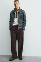 Pantalón de hombre color marrón oscuro, de corte balloon fit, con cintura con trabillas y cierre frontal de botón y cremallera. Presenta bolsillos delanteros y bolsillos traseros de vivo.