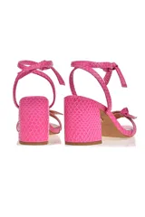Sandalia de tacón color rosa con estampado de piel de serpiente, tira delantera con nudo y tira para atar al tobillo.