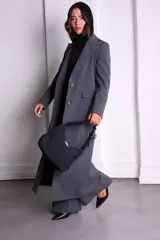 Bolso de nylon negro con textura sutil, manija fruncida y correa ajustable para usar como bandolera o mini bag.