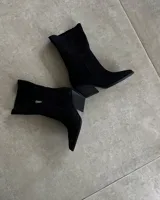 Botas de caña media color negro, confeccionadas en gamuza, con punta fina y taco geométrico.