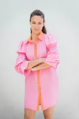 Vestido camisero corto color naranja, con cuello y abotonadura frontal en color crudo. Tiene mangas largas abullonadas con puños fruncidos.