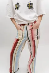 Pantalón de gabardina de tiro medio con diseño de rayas verticales en tonos rosado, rojo, celeste, beige y negro. Cuenta con bolsillos frontales aplicados y cierre con botón.