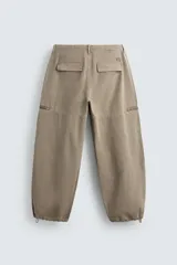 Pantalón cargo de corte relajado con efecto lavado, confeccionado en tejido de algodón. Presenta bolsillos frontales, bolsillos traseros con solapa y bolsillos con cierre de cremallera en las perneras. Incluye pliegues en las rodillas y ajuste en los tobillos.