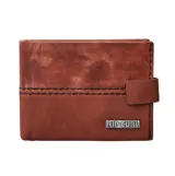 Billetera Rip Curl de cuero genuino color marrón, con cierre de presilla lateral y placa metálica con el logo de la marca en el frente. Cuenta con costuras decorativas contrastantes y protección RFID.