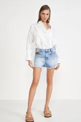 Short de jean celeste claro con efecto desgastado, tiro medio y ruedo deshilachado. Incluye un llavero con la inicial 'M' en el pasacinto y un forro de bolsillo con estampado de monograma.