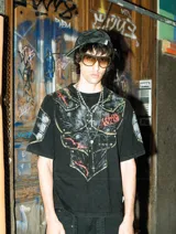 Remera de algodón con efecto acid wash y corte boxy fit. Presenta un estampado frontal que simula una armadura medieval con detalles en rojo y remaches, extendiéndose hacia las mangas.