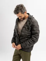 Campera puffer negra con diseño capitoneado, cierre frontal completo y capucha integrada.