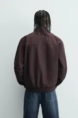 Cazadora azul marino de corte regular fit, confeccionada en tejido técnico repelente al agua. Presenta cuello subido, manga larga, bolsillos de vivo en cadera, bolsillo interior y acabados en rib en puños y bajo. Cierre frontal de cremallera oculta por solapa con botones a presión.