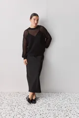 Falda midi color negro al bies, confeccionada en tela de textura suave y caída fluida, de diseño minimalista y silueta recta.