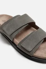 Sandalias de hombre color beige, fabricadas en piel con acabado serraje. Cuentan con dos tiras anchas ajustables mediante cierres adherentes y plantilla con horma anatómica.