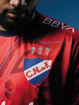 Camiseta de fútbol Umbro de arquero del Club Nacional de Football, modelo Oficial 2025. Diseño con patrón gráfico en tonos azules y detalles en rojo en cuello y mangas. Incluye logo de Umbro, escudo del club y sponsor Antel en el frente.