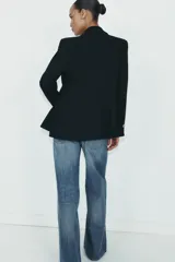 Blazer cruzado color beige, de manga larga, con cuello solapa y forro interior negro. Presenta cierre frontal con botones dorados y bolsillos de vivo en el pecho y bolsillos con solapa en el delantero.