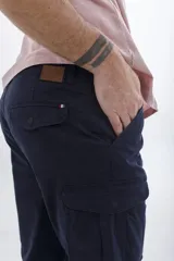 Pantalón cargo color verde militar, de corte recto y ajuste slim, con bolsillos laterales con solapa y cierre frontal.