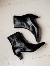 Bota corta de cuero negro con punta fina y taco bajo tipo kitten heel.