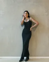 Vestido largo negro de silueta ajustada con aplicación de strass brillante y mangas amplias de red transparente. Incluye una pieza interior básica de color negro.