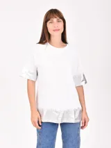 Remera blanca de corte holgado con detalles metalizados en color dorado en el ruedo y en los extremos de las mangas. Presenta un sutil estampado de texto en el pecho.