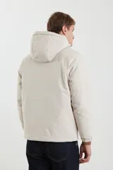 Campera impermeable negra con capucha, cierres a tono y cursores negros metalizados, bolsillos frontales con tapa, elásticos regulables en el ruedo e interior térmico con detalles confeccionados con láser.