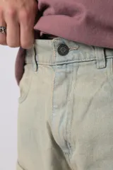 Jean baggy de corte holgado con múltiples bolsillos cargo frontales con cierre metálico. Presenta un acabado lavado, tiro medio y tiras de ajuste en la botamanga.