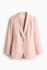 Blazer de botonadura sencilla en color rosado, con solapas de pico, bolsillos delanteros ribeteados y cierre de un botón. Cuenta con hombreras, forro interior y abertura en la parte trasera.