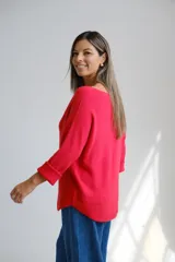 Sweter de punto color rojo, con escote a la base y mangas largas con puños doblados. Presenta un corte holgado y diseño básico.