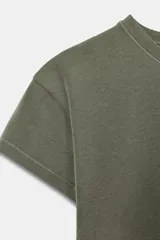 Camiseta de corte entallado confeccionada en mezcla de algodón, con cuello redondo y mangas cortas. Presenta un diseño básico de bajo recto en color gris oscuro.