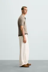 Polo de punto negro, manga corta, con cuello solapa y cierre frontal de tres botones. Presenta un calce regular y acabados en rib en mangas y ruedo.