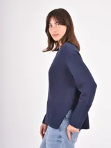 Buzo de tejido de punto color negro, con cuello redondo, mangas largas y puños anchos acanalados. Presenta un diseño con ruedo asimétrico y aberturas laterales.