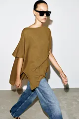Top tipo capa blanco de punto fluido, con mezcla de viscosa, cuello bote, mangas cortas y bajo asimétrico.