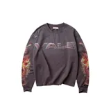 Remera de manga larga color negro con efecto lavado, cuello redondo y detalles desgastados en los bordes. Presenta un estampado frontal con la palabra 'VALE' en tipografía metálica y un diseño de llamas en ambas mangas.