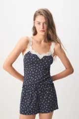 Pijama corto de color azul marino con pequeño estampado floral blanco, compuesto por una musculosa con detalles de encaje en el escote y un short con cordón ajustable en la cintura.