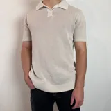 Chomba de tejido de punto con textura, color beige, de manga corta y cuello polo con cierre frontal parcial.