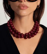 Collar de doble vuelta compuesto por cuentas esféricas de color bordó con acabado brillante.