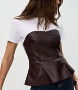 Blusa peplum sin breteles confeccionada en PU color bordó, con escote corazón y cierre posterior por cremallera. Presenta un diseño estructurado con ruedo evasé.