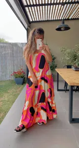 Vestido largo sin mangas, con escote cuadrado y falda con volado en el ruedo. Presenta un estampado abstracto y psicodélico en tonos fucsia, naranja, blanco y negro.