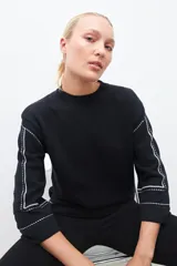 Sweater negro de tejido de punto con cuello redondo y mangas largas. Presenta bordado en contraste color blanco en los hombros y mangas.