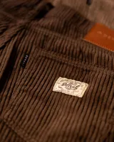 Pantalón de pana marrón con diseño de cinco bolsillos y corte clásico.