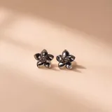 Aros tipo botón en plata 925, con diseño de flor de cinco pétalos texturizados.