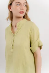 Blusa blanca de lino con escote en V abotonado y mangas cortas arremangadas.