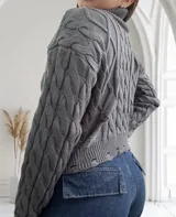Sweater gris de punto trenzado, con cuello alto y terminaciones rotas.