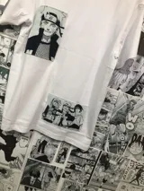 Remera blanca de algodón con cuello redondo y mangas cortas. Presenta un estampado rectangular con personajes de Naruto y un parche con el rostro de Naruto.